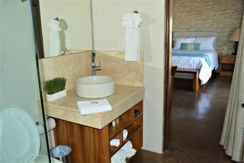 a bathroom with a sink and a mirror and a bed at San Angel Suites in Cabo San Lucas