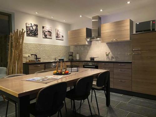 una cocina con una gran mesa de madera y sillas en vakantiewoning le jardin de grand-mére en Oudenburg