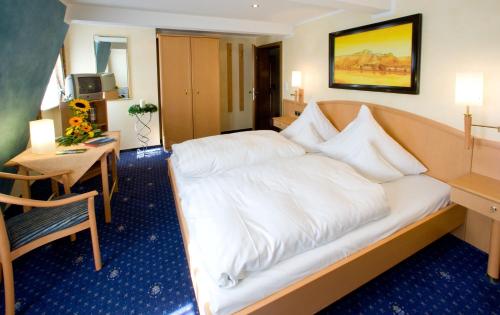 una camera d'albergo con un letto bianco e un tavolo di Landgasthof Rebstock a Sankt Goar