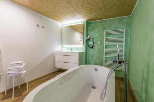a bathroom with a white tub and a green wall at Palác Daun - Studio Apartments in Znojmo