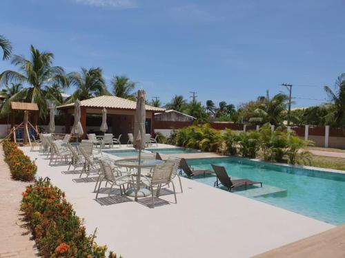 a resort with a pool and chairs and a table at Praia de Itacimirim - Praia da Espera in Itacimirim