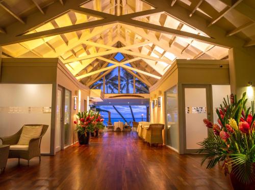 a lobby with a wooden ceiling with chairs and flowers at Little Polynesian Resort in Rarotonga