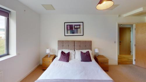 a bedroom with a large bed with purple pillows at Niche Parkview Apartments in Brentwood