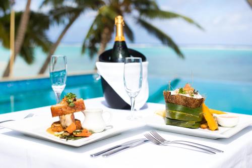 a table with two plates of food and a bottle of wine at Little Polynesian Resort in Rarotonga