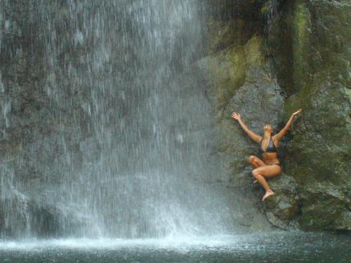 a woman sitting on a rock next to a waterfall at Anamaya Resort in Montezuma