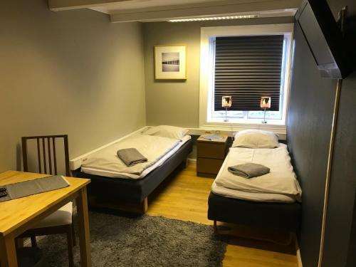 two beds in a room with a table and a window at Taras Rom og leiligheter in Kragerø