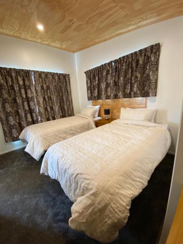 two beds in a bedroom with two windows at Country Retreats on Ranzau 2 in Nelson