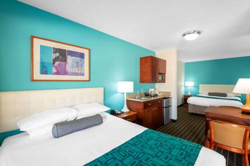 a hotel room with two beds and blue walls at Howard Johnson by Wyndham St. George Hotel & Suites in St. George