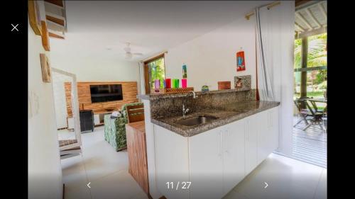 a kitchen with a sink and a living room at Bangalô duplex à beira-mar in Camaçari