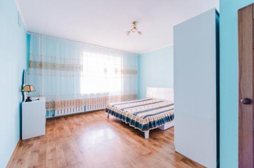 a blue bedroom with a bed and a window at Dekabrist Apartment at anokhina 93 in Chita