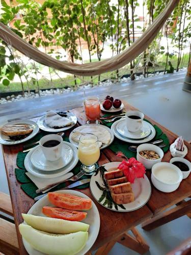 une table avec des assiettes de nourriture et des tasses de café dans l'établissement Pousada NÔ Caraíva, à Caraíva