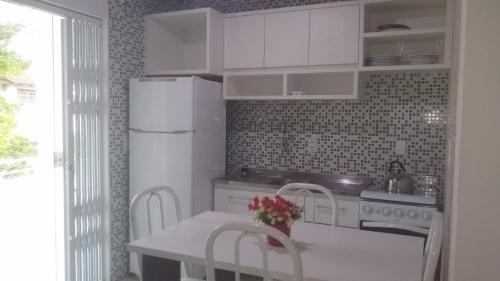Apartamento com varanda في فلوريانوبوليس: مطبخ مع ثلاجة بيضاء وطاولة مع كراسي