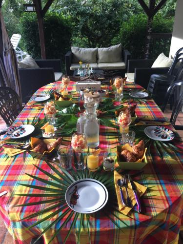 een tafel met een kleurrijk tafelkleed met voedsel erop bij Villa du Moulin de Saint Félix in Le Gosier