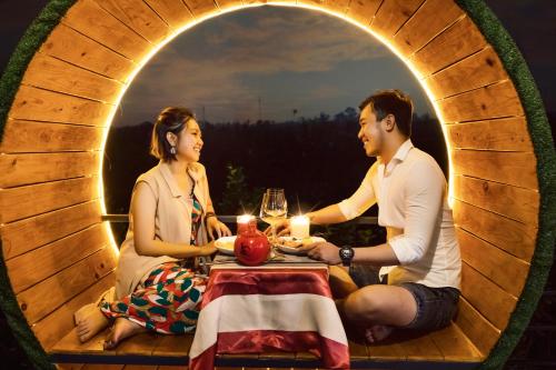 a man and a woman sitting at a table in a round room at Cồn Phụng Resort Mekong - Nature Escape with Free Boat Shuttle & Fishing in Ben Tre