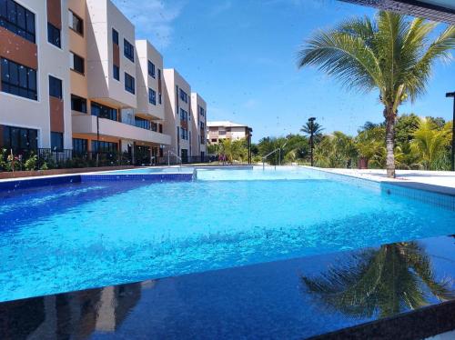 a large swimming pool in front of a building at Flat Cantinho do Paraíso in Guarajuba
