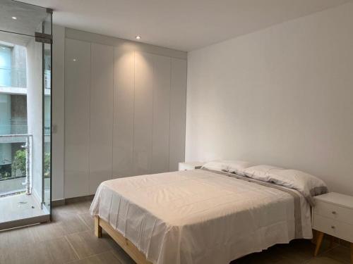 a white bedroom with a bed and a window at Vive - Descansa - Disfruta in San Bartolo