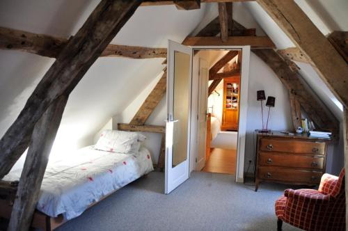 a bedroom with a bed and a dresser in a attic at Au Fond du Jardin Maison d'hôtes in Saint-Saëns
