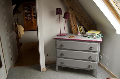 a bedroom with a dresser with a lamp and books at Au Fond du Jardin Maison d'hôtes in Saint-Saëns