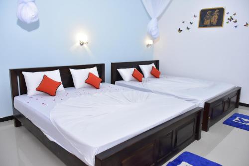 two beds in a room with red and white pillows at La Casa Safari Resort in Udawalawe