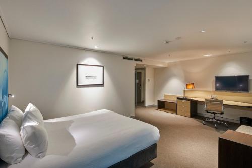 a hotel room with a bed and a desk at Novotel Melbourne On Collins in Melbourne