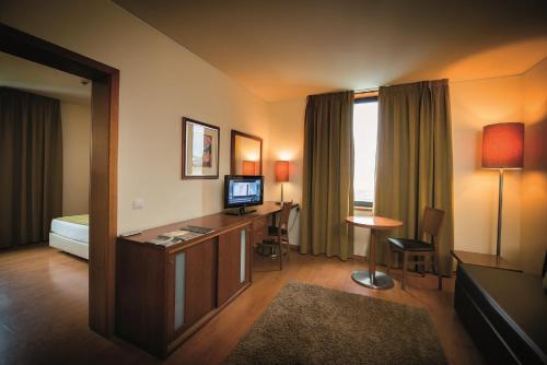a hotel room with a bed and a desk with a television at Vila Gale Opera in Lisbon