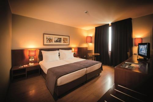 a hotel room with a bed and a television at Vila Gale Opera in Lisbon