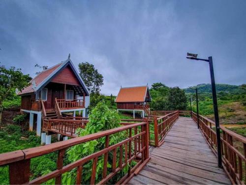 une passerelle en bois menant à une maison éclairée dans l'établissement Greenhouse Retreat, à Saen Monourom