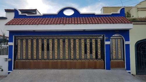 a blue and white garage with a gate and a red roof at Casa amueblada - Mazatlán in Mazatlán