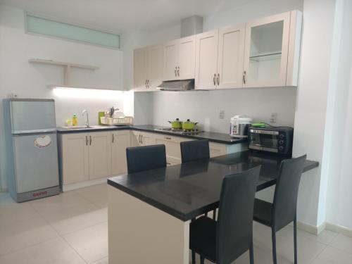 uma cozinha com armários brancos e uma mesa e cadeiras pretas em Citihouse Ho Chi Minh Apartment em Cidade de Ho Chi Minh