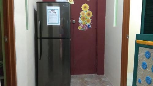 un frigorifero in acciaio inossidabile davanti a una porta rossa di Eiffel Residence Cideng - Female Only a Giacarta