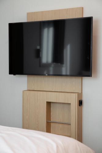 a flat screen tv on top of a wooden stand at Busan Lounge 26 Hotel in Busan