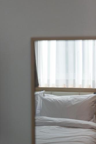 a bed with white sheets and a window at Busan Lounge 26 Hotel in Busan