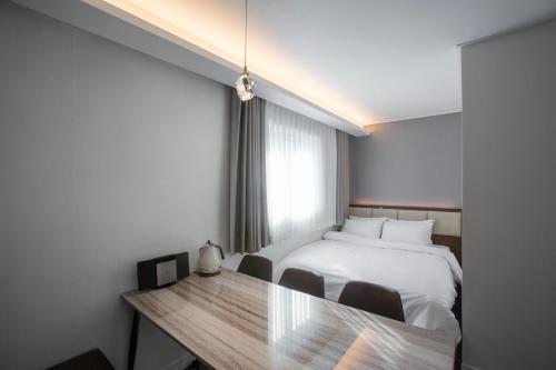 a bedroom with a bed and a table with chairs at Busan Lounge 26 Hotel in Busan