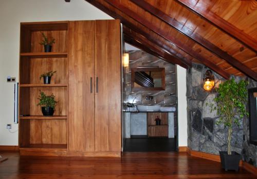 una cocina con armarios de madera y una pared de piedra. en Cottage San Francesco en Nuwara Eliya