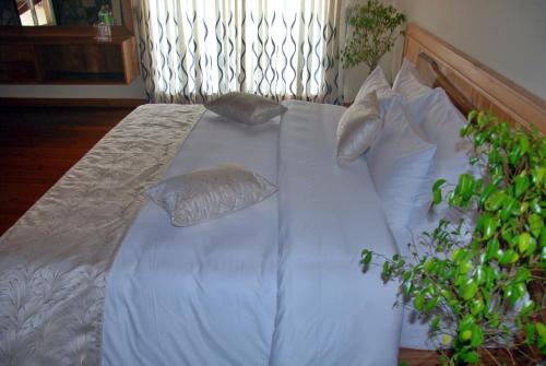 a large bed with white sheets and pillows at Cottage San Francesco in Nuwara Eliya