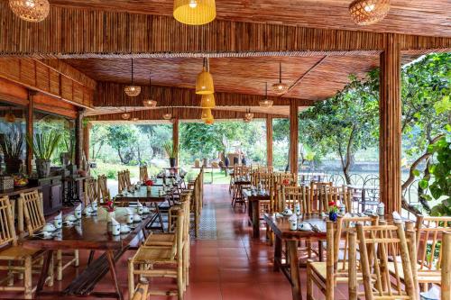 un restaurante con mesas de madera, sillas y árboles en An's Eco Garden Resort en Ninh Binh