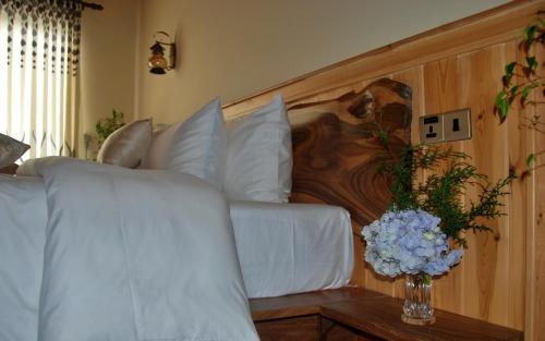 a bedroom with a white bed with a vase of flowers at Cottage San Francesco in Nuwara Eliya