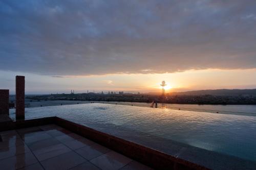 a pool on the roof of a building with the sunset at Candeo Hotels Nankai Wakayama in Wakayama