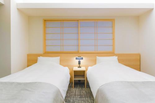two beds in a room with a window at Hotel M's Est Shijo Karasuma in Kyoto