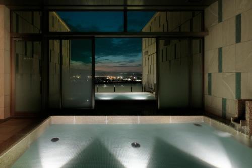 a bath room with a tub and a window at Candeo Hotels Nankai Wakayama in Wakayama