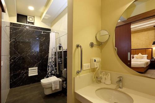 コッタヤムにあるHotel New York Squareのバスルーム(洗面台、トイレ、鏡付)