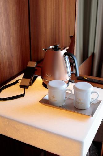 a tea kettle and two cups sitting on a table at Candeo Hotels Nankai Wakayama in Wakayama