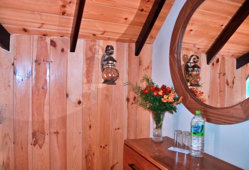 a wooden wall with a mirror and a vase of flowers at Cottage San Francesco in Nuwara Eliya