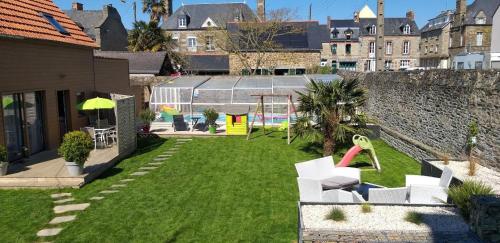 une cour avec une aire de jeux avec des chaises blanches et une aire de jeux dans l'établissement L'Âme du Gourmand, à Pontorson