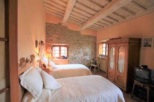 una camera con due letti e un muro di pietra di Antico Gelso a Todi