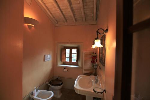 een badkamer met 2 wastafels, een toilet en een raam bij Antico Gelso in Todi