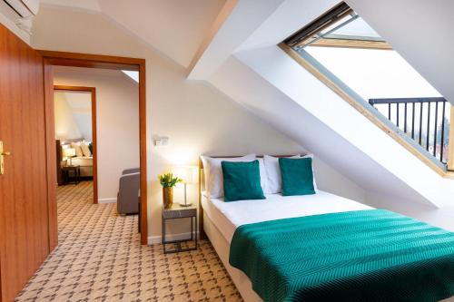 a bedroom with a bed with green sheets and a window at Hotel Verde Montana Wellness & Spa in Kudowa-Zdrój