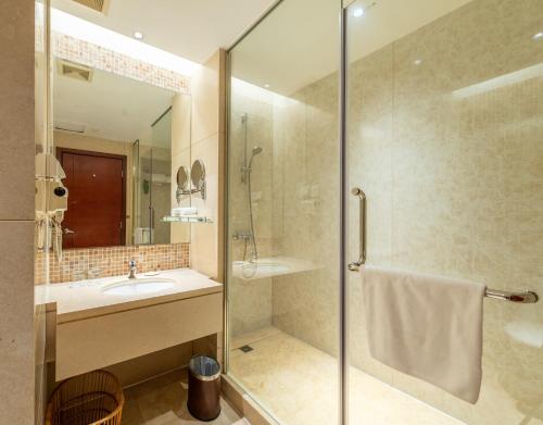 y baño con ducha acristalada y lavamanos. en Guangzhou Baiyun International Convention Center, en Guangzhou