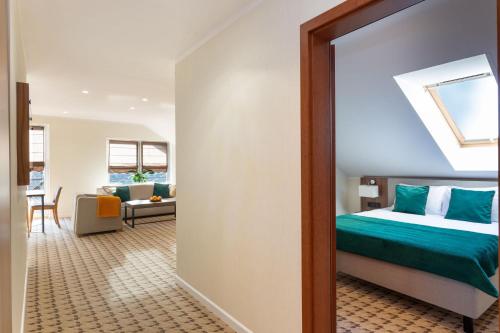 a room with a bed and a living room at Hotel Verde Montana Wellness & Spa in Kudowa-Zdrój