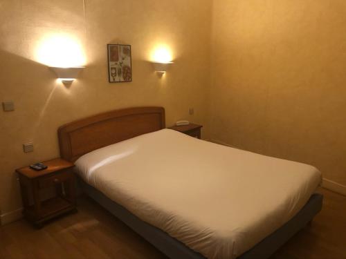 Bett in einem Zimmer mit zwei Lichtern an der Wand in der Unterkunft Hôtel des Couronnes Châteaudun in Châteaudun